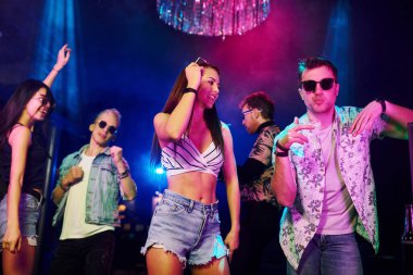 Gençler gece kulübünde renkli lazer ışıklarıyla eğleniyorlar..