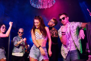 Gençler gece kulübünde renkli lazer ışıklarıyla eğleniyorlar..