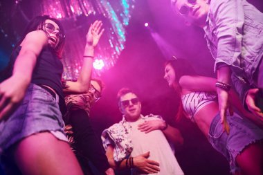 Gece kulübünde renkli lazer ışıklarıyla eğlenen gençlerin manzarası.