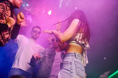 Gençler gece kulübünde renkli lazer ışıklarıyla eğleniyorlar..