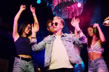 Gençler gece kulübünde renkli lazer ışıklarıyla eğleniyorlar..