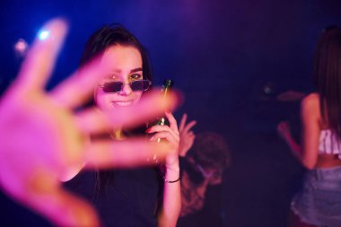 Odaklanmamış el. Gençler gece kulübünde renkli lazer ışıklarıyla eğleniyorlar..