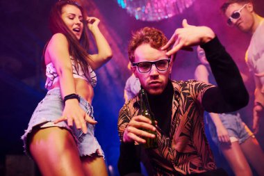 Dans eden ve poz veren aktif bir çift. Gençler gece kulübünde renkli lazer ışıklarıyla eğleniyorlar..