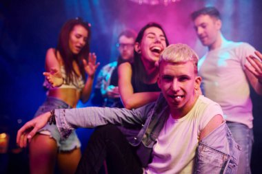 Uyuşturucu hapı alan adam. Gençler gece kulübünde renkli lazer ışıklarıyla eğleniyorlar..