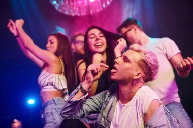 Uyuşturucu hapı alan adam. Gençler gece kulübünde renkli lazer ışıklarıyla eğleniyorlar..