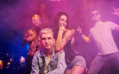 Çılgına dönüp kameraya poz vermek. Gençler gece kulübünde renkli lazer ışıklarıyla eğleniyorlar..