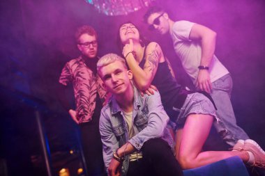 Çılgına dönüp kameraya poz vermek. Gençler gece kulübünde renkli lazer ışıklarıyla eğleniyorlar..