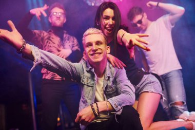 Çılgına dönüp kameraya poz vermek. Gençler gece kulübünde renkli lazer ışıklarıyla eğleniyorlar..