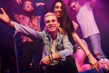 Çılgına dönüp kameraya poz vermek. Gençler gece kulübünde renkli lazer ışıklarıyla eğleniyorlar..