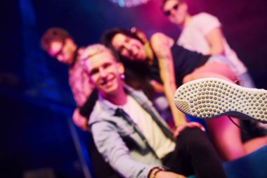 Çılgına dönüp kameraya poz vermek. Gençler gece kulübünde renkli lazer ışıklarıyla eğleniyorlar..