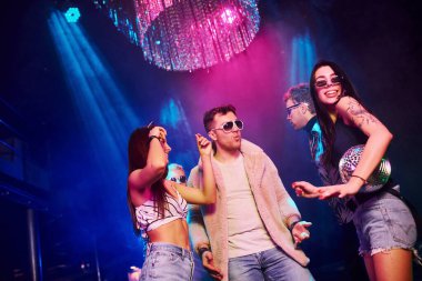 Güneş gözlüklü şık adam kendini patron gibi hissediyor. Gençler gece kulübünde renkli lazer ışıklarıyla eğleniyorlar..