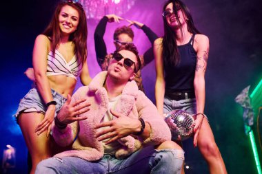 Güneş gözlüklü şık adam kendini patron gibi hissediyor. Gençler gece kulübünde renkli lazer ışıklarıyla eğleniyorlar..