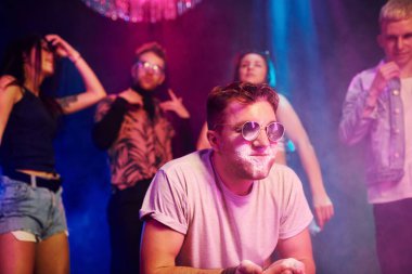 Güneş gözlüklü genç adam gece kulübünde arkadaşlarıyla uyuşturucu kokluyor..