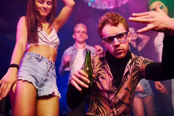Dans eden ve poz veren aktif bir çift. Gençler gece kulübünde renkli lazer ışıklarıyla eğleniyorlar..