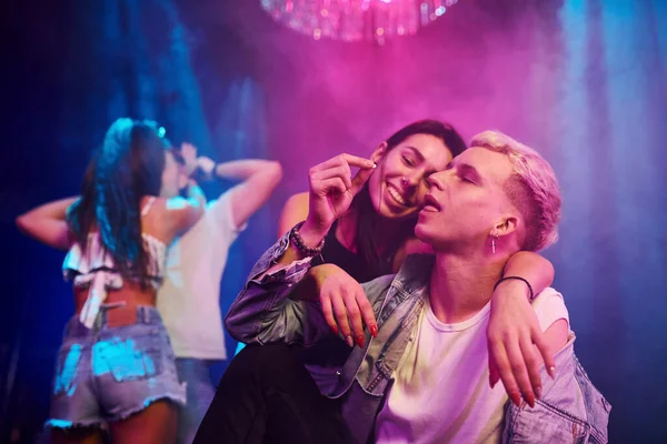 Uyuşturucu hapı alan adam. Gençler gece kulübünde renkli lazer ışıklarıyla eğleniyorlar..