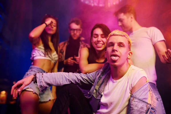 Uyuşturucu hapı alan adam. Gençler gece kulübünde renkli lazer ışıklarıyla eğleniyorlar..