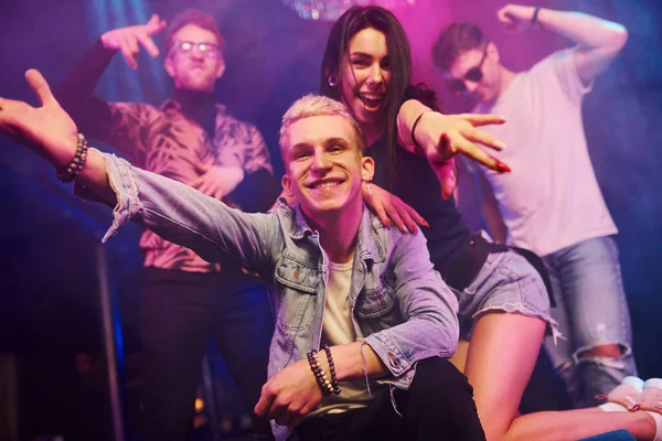 Çılgına dönüp kameraya poz vermek. Gençler gece kulübünde renkli lazer ışıklarıyla eğleniyorlar..