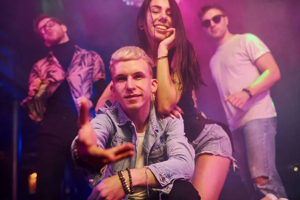 Çılgına dönüp kameraya poz vermek. Gençler gece kulübünde renkli lazer ışıklarıyla eğleniyorlar..