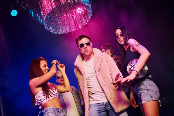 Güneş gözlüklü şık adam kendini patron gibi hissediyor. Gençler gece kulübünde renkli lazer ışıklarıyla eğleniyorlar..