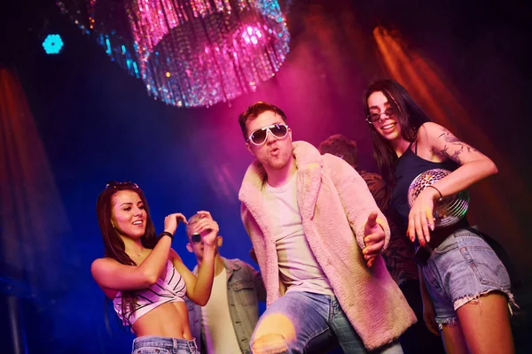 Güneş gözlüklü şık adam kendini patron gibi hissediyor. Gençler gece kulübünde renkli lazer ışıklarıyla eğleniyorlar..