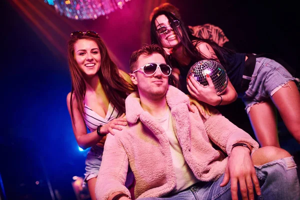 Güneş gözlüklü şık adam kendini patron gibi hissediyor. Gençler gece kulübünde renkli lazer ışıklarıyla eğleniyorlar..