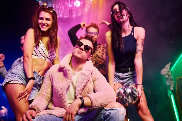 Güneş gözlüklü şık adam kendini patron gibi hissediyor. Gençler gece kulübünde renkli lazer ışıklarıyla eğleniyorlar..