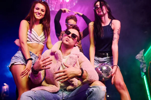 Güneş gözlüklü şık adam kendini patron gibi hissediyor. Gençler gece kulübünde renkli lazer ışıklarıyla eğleniyorlar..