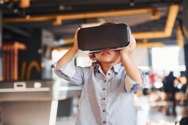 Sanal gerçeklik gözlüklü çocuk ve günlük giysiler içinde oyun odasında iyi eğlenceler..