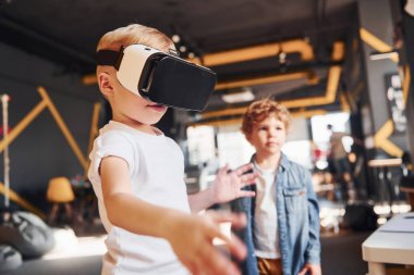 Sanal gerçeklik gözlüklü çocuk ve günlük giysiler içinde oyun odasında iyi eğlenceler..