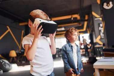 Sanal gerçeklik gözlüklü çocuk ve günlük giysiler içinde oyun odasında iyi eğlenceler..