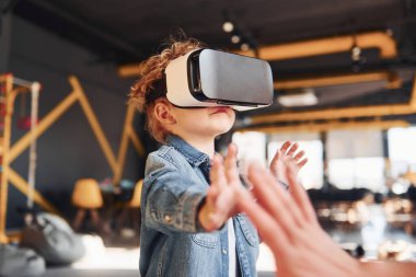 Sanal gerçeklik gözlüklü çocuk ve günlük giysiler içinde oyun odasında iyi eğlenceler..
