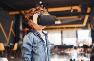 Sanal gerçeklik gözlüklü çocuk ve günlük giysiler içinde oyun odasında iyi eğlenceler..