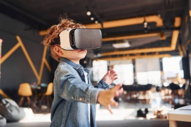 Sanal gerçeklik gözlüklü çocuk ve günlük giysiler içinde oyun odasında iyi eğlenceler..