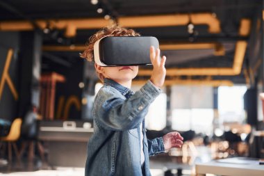Sanal gerçeklik gözlüklü çocuk ve günlük giysiler içinde oyun odasında iyi eğlenceler..