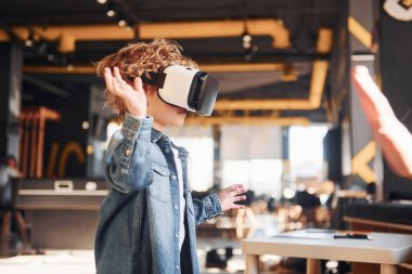 Sanal gerçeklik gözlüklü çocuk ve günlük giysiler içinde oyun odasında iyi eğlenceler..