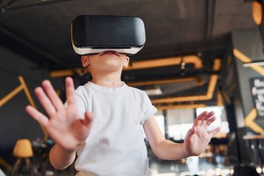 Sanal gerçeklik gözlüklü çocuk ve günlük giysiler içinde oyun odasında iyi eğlenceler..