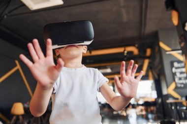 Sanal gerçeklik gözlüklü çocuk ve günlük giysiler içinde oyun odasında iyi eğlenceler..