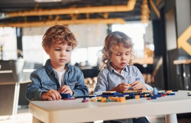 Küçük arkadaşlar oyun odasında inşaat oyuncaklarıyla eğleniyor. Anaokulu eğitim oyunları.