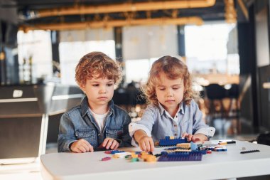 Küçük arkadaşlar oyun odasında inşaat oyuncaklarıyla eğleniyor. Anaokulu eğitim oyunları.