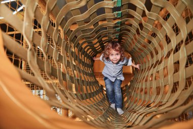 Child have fun in playroom by going through the wooden cage.