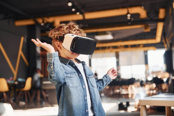 Sanal gerçeklik gözlüklü çocuk ve günlük giysiler içinde oyun odasında iyi eğlenceler..