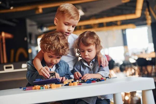 Küçük arkadaşlar oyun odasında inşaat oyuncaklarıyla eğleniyor. Anaokulu eğitim oyunları.