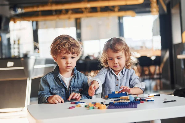 Küçük arkadaşlar oyun odasında inşaat oyuncaklarıyla eğleniyor. Anaokulu eğitim oyunları.