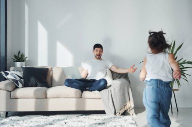 Mutlu baba ve kızı evde dizüstü bilgisayarla vakit geçiriyorlar..