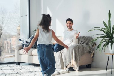 Happy father with his daughter spending free time with laptop at home together.