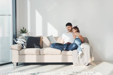 Mutlu baba ve kızı evde dizüstü bilgisayarla vakit geçiriyorlar..