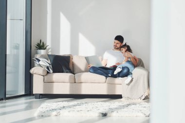 Mutlu baba ve kızı evde dizüstü bilgisayarla vakit geçiriyorlar..
