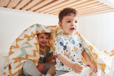 İki küçük çocuk dinleniyor ve yatak odasında birlikte eğleniyorlar..