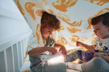 İki küçük çocuk dinleniyor ve battaniyenin altında birlikte eğleniyorlar..