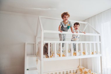 İki küçük çocuk dinleniyor ve yatak odasında birlikte eğleniyorlar. Onların yanında oturan kedi..